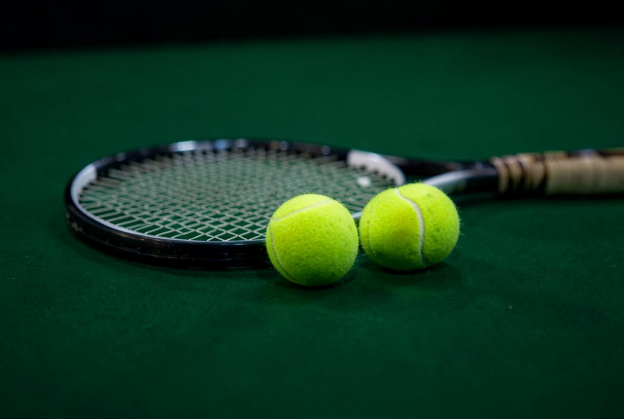 Tennisracket och bollar på en grön inomhusbana